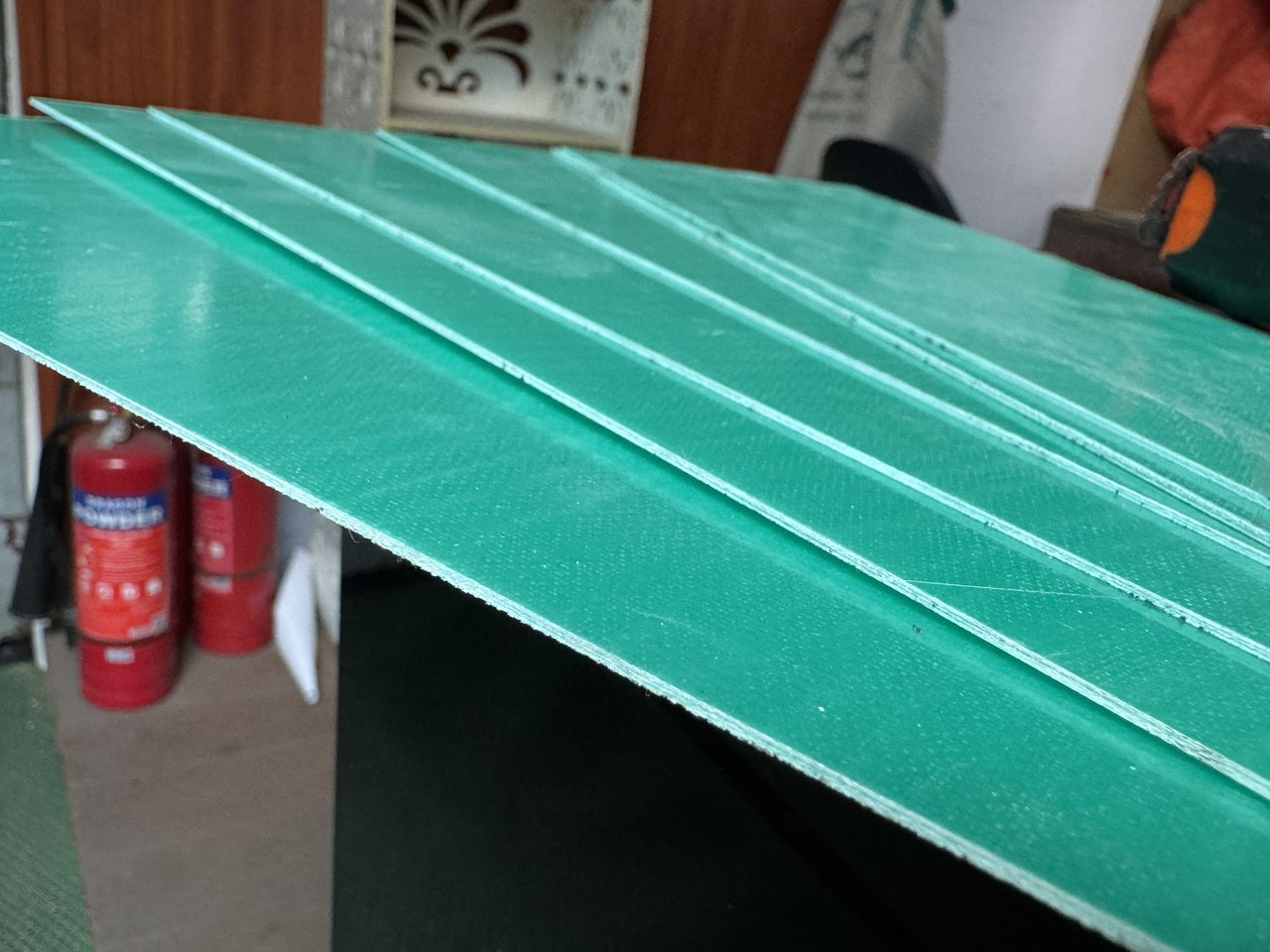 Các tấm phíp xanh ngọc mỏng xếp chồng lệch nhau trong kho, thấy mép tấm sáng màu